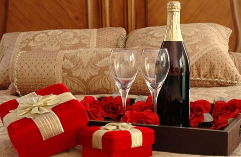 Wine glasses and bottle of wine in tray on bed