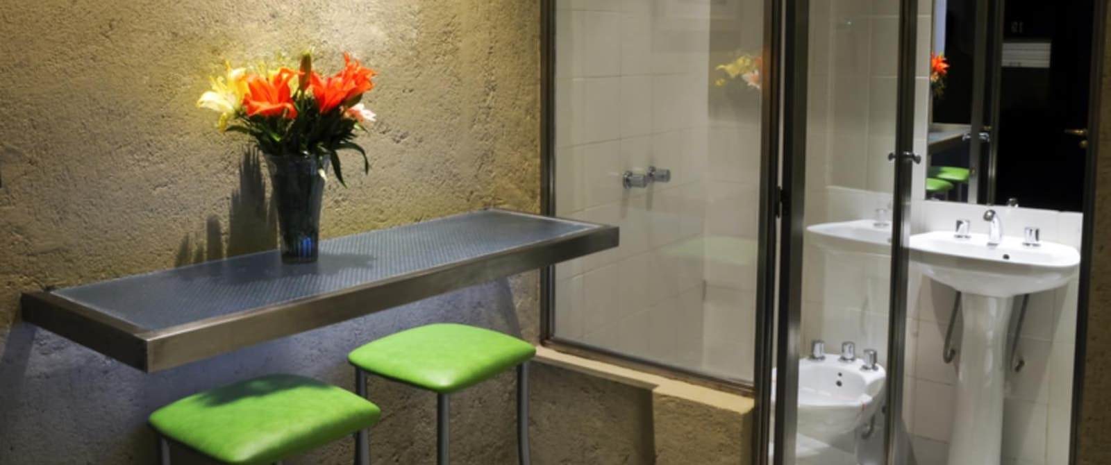 Sitting area with green cushioned bar stools and view into bathroom